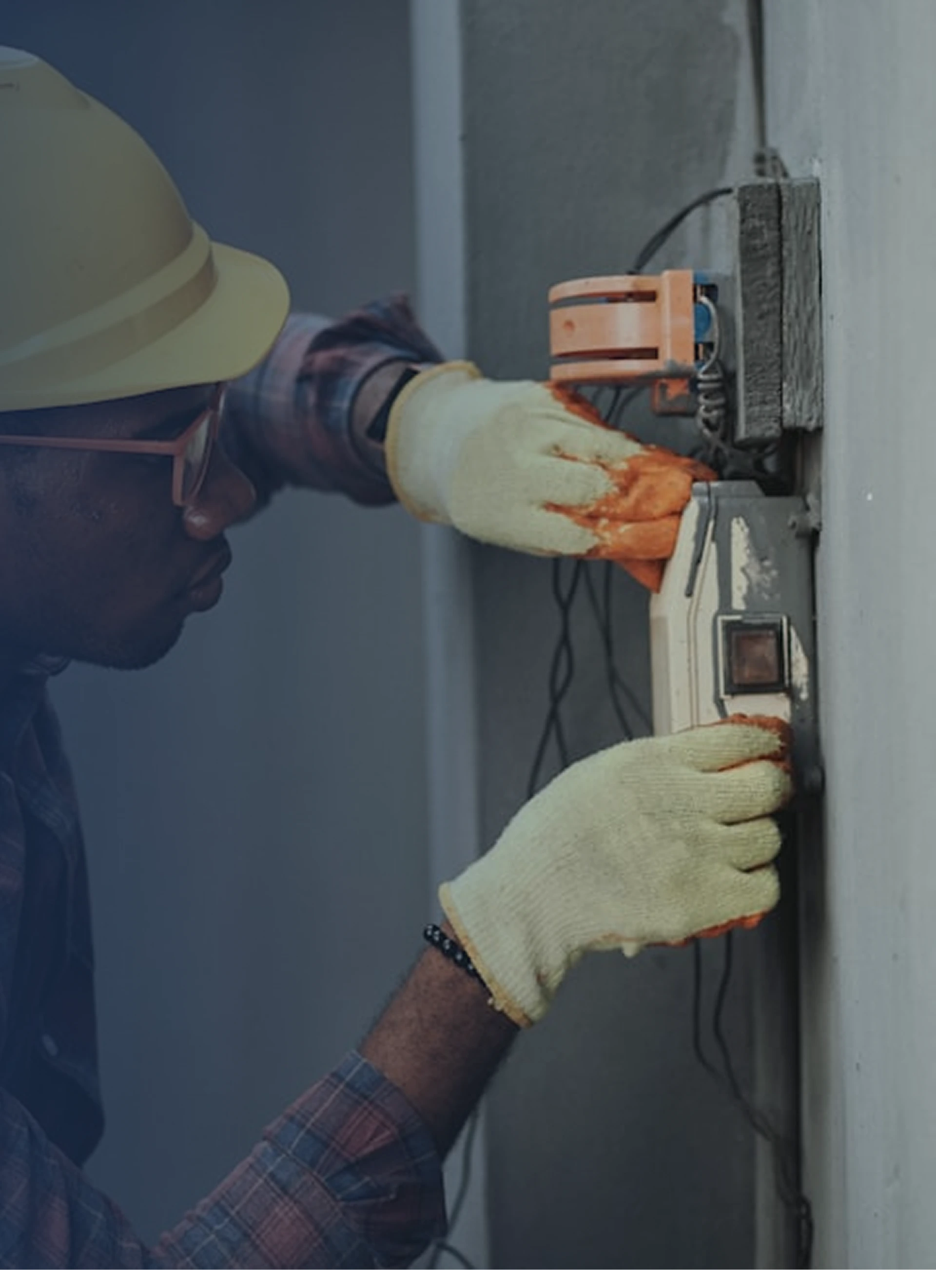 Electrical worker in safety gear working on an electrical panel