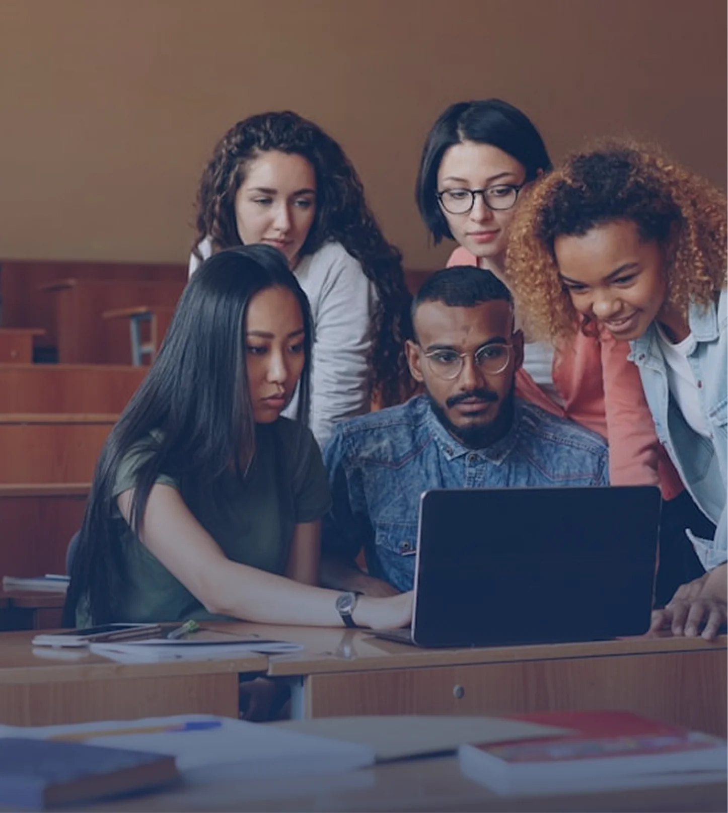 Diverse group of students collaborating around a laptop